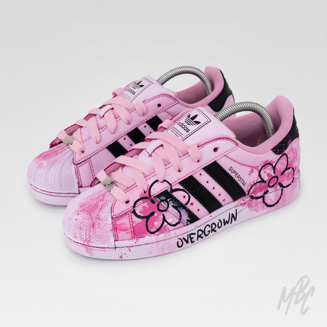 Front three-quarter view of Pink Overgrown custom Adidas Superstar featuring pink floral artwork, textured paint finish and pastel pink laces.