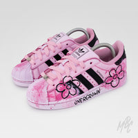 Front three-quarter view of Pink Overgrown custom Adidas Superstar featuring pink floral artwork, textured paint finish and pastel pink laces.