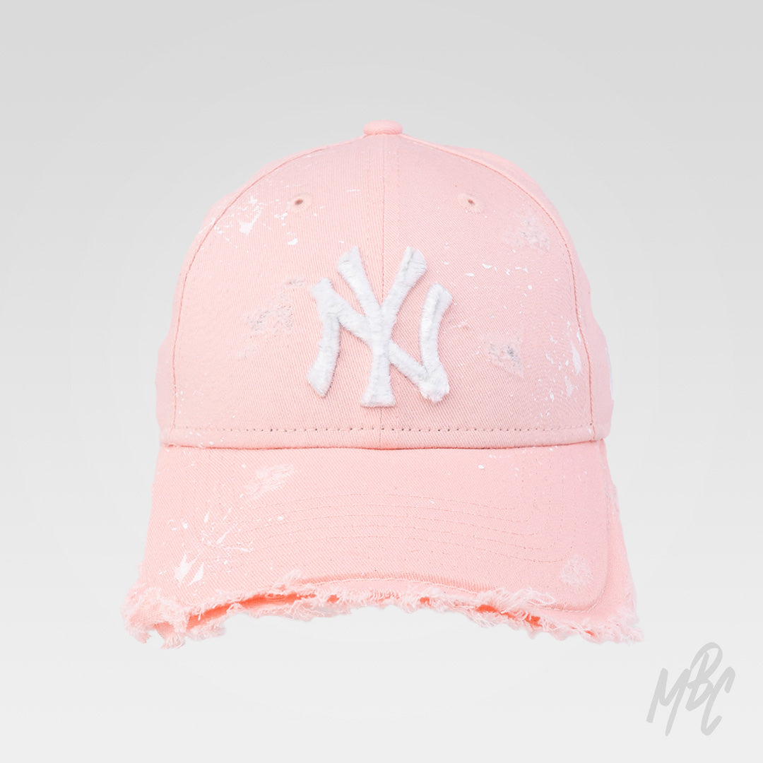 Pink Raw Edge custom New Era NY cap featuring a distressed frayed brim, white embroidered logo and hand-painted white paint splatter detailing.