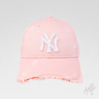Pink Raw Edge custom New Era NY cap featuring a distressed frayed brim, white embroidered logo and hand-painted white paint splatter detailing.