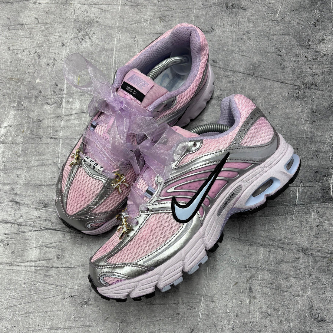 Pink Nike Moto 2 trainers styled with lilac organza ribbon laces, personalised lace tags and gold lace charms from the Lace Charm Pack