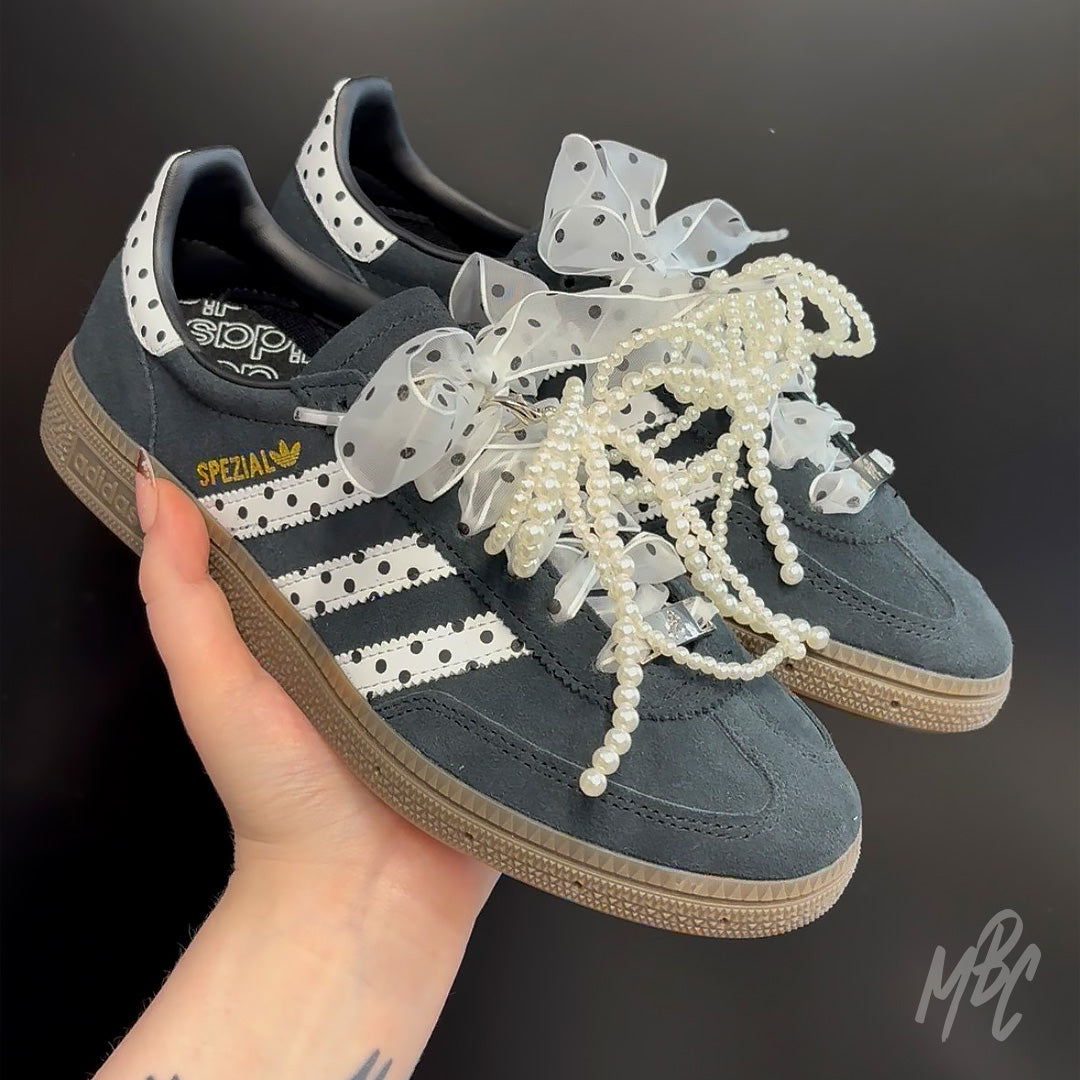 Hand holding custom Adidas Spezial polka dot trainers with pearl laces and ribbon bow detailing