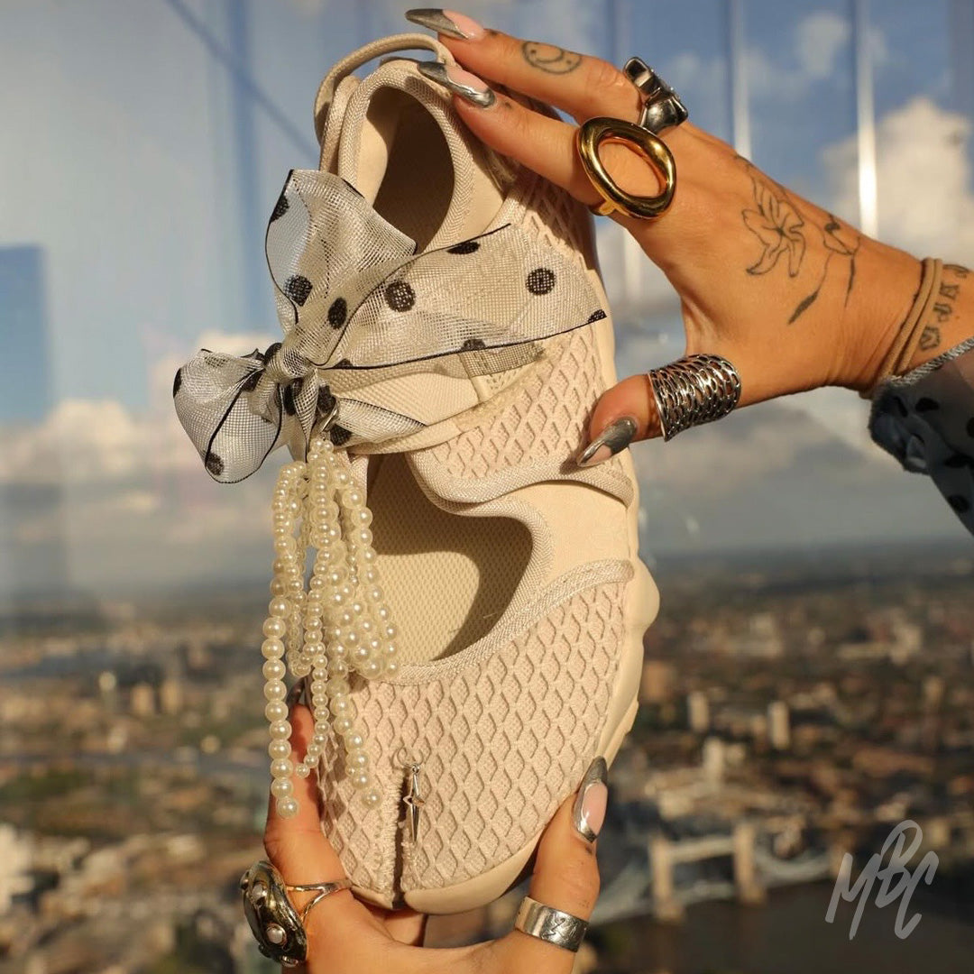 Beige Nike Air Rift trainers with sheer polka dot ribbon laces, pearl lace charms and decorative sneaker accessories
