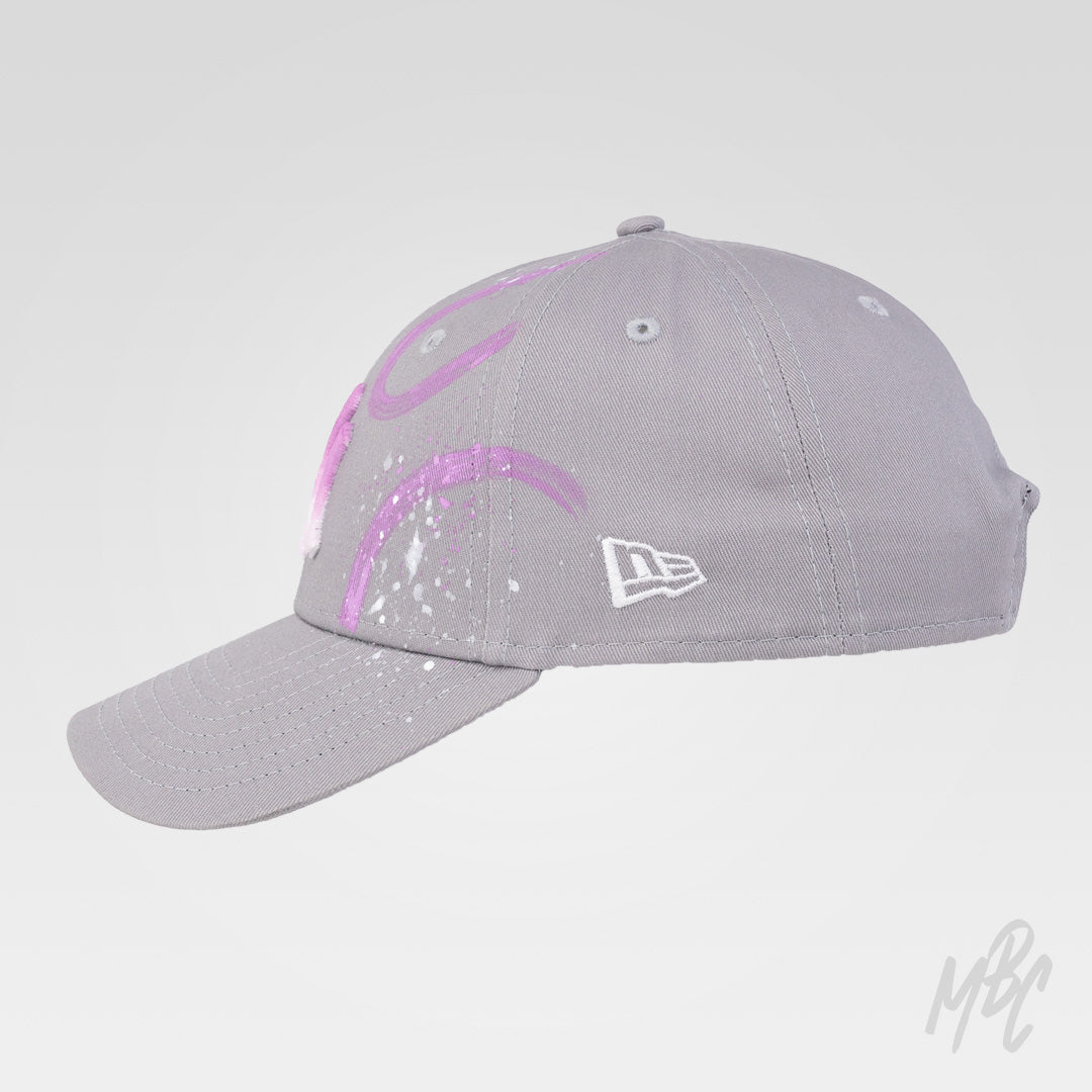 Side view of the Gradient Swipe custom New Era NY cap with abstract pink and purple hand-painted swipes and white paint splatter details.