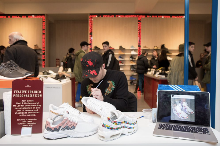 An artist live hand painting custom Nike trainers at an Offspring store in Selfridges