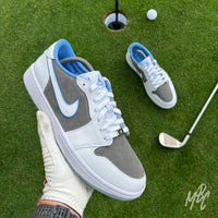 Slate Suede custom Jordan 1 Low Golf shoes held above a putting green, featuring premium grey suede, white leather and light blue detailing.