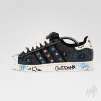 Outside view of Stardust Denim custom Adidas Superstar with distressed black denim, colourful gem embellishments, blue paint splatters and hand-painted graphics.