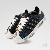 Pair of Stardust Denim custom Adidas Superstar trainers featuring distressed black denim, hand-painted stars, colourful gem detailing, paint splatters and custom lace beads.