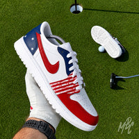 Stateside Drive custom Jordan 1 Low Golf shoes with hand-painted USA-inspired detailing, photographed on a golf course putting green beside the hole and flag.