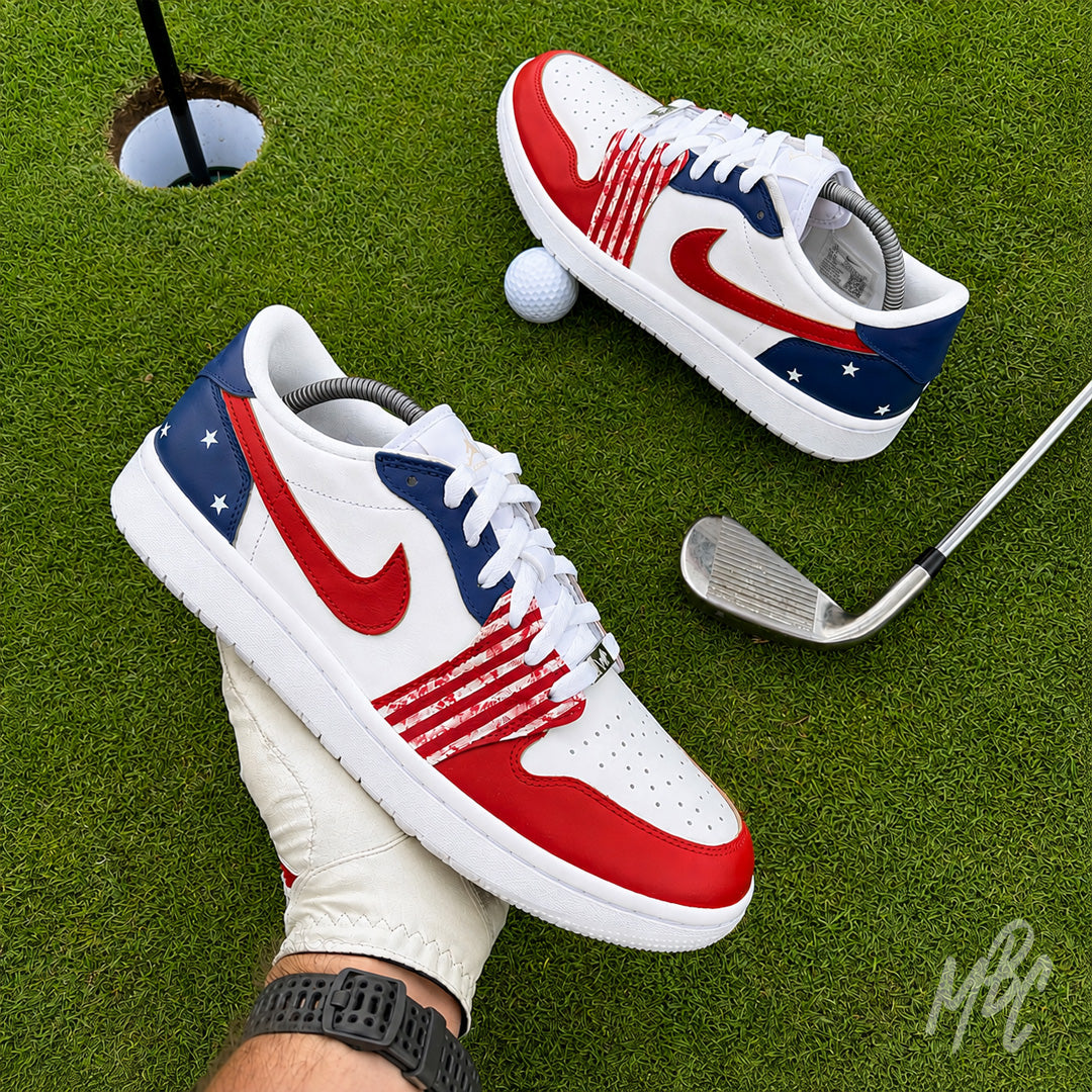 Stateside Drive custom Jordan 1 Low Golf shoes held above a putting green, featuring hand-painted patriotic red, white and blue with a golf club and golf ball.