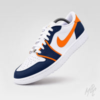 Angled front view of a white Air Jordan 1 Low Golf shoe with navy overlays, bright orange trim and Nike Swoosh, white laces, and a perforated toe box.