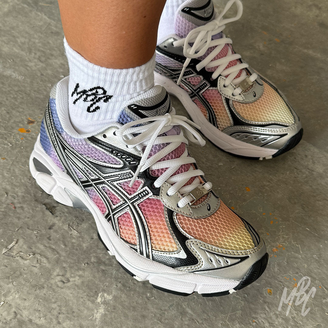 Sunset Dip Dye ASICS GT-2160 custom trainers worn on foot, featuring a hand-painted sunset gradient fade blending yellow, orange, pink and purple across the breathable mesh upper.
