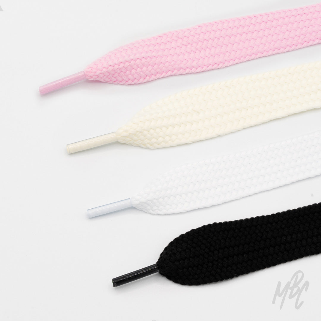 Four wide, thick-weave shoelaces in pink, cream, white, and black with matching plastic aglets, arranged on a white background.