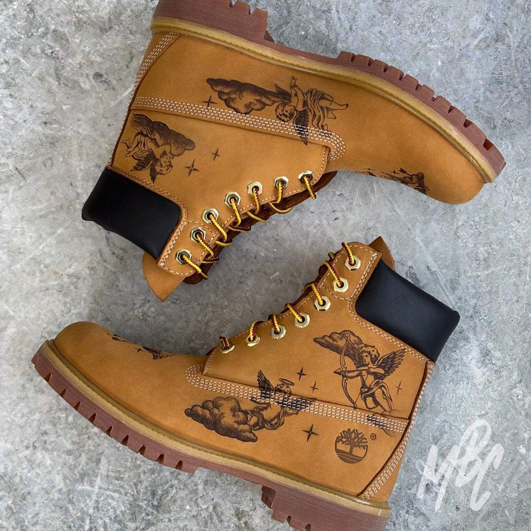 Tattoo-style cherub illustrations engraved into tan Timberland 6 Inch boots using pyrography for a permanent suede finish