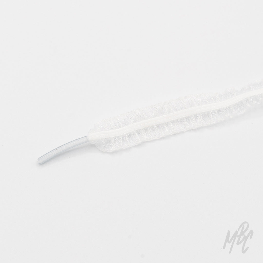 Close-up of a white mesh shoelace with ruffled edges and a clear plastic aglet on a white background.