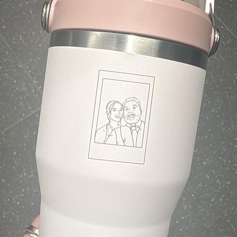 White tumbler with a engraved design of two people on a gray surface