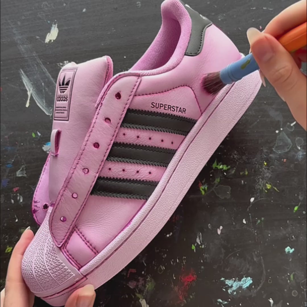 Video showing the making process of the Pink Overgrown custom Adidas Superstar, featuring hand-painted pink brushstrokes, illustrated flowers and detailed finishing touches before the completed custom trainers